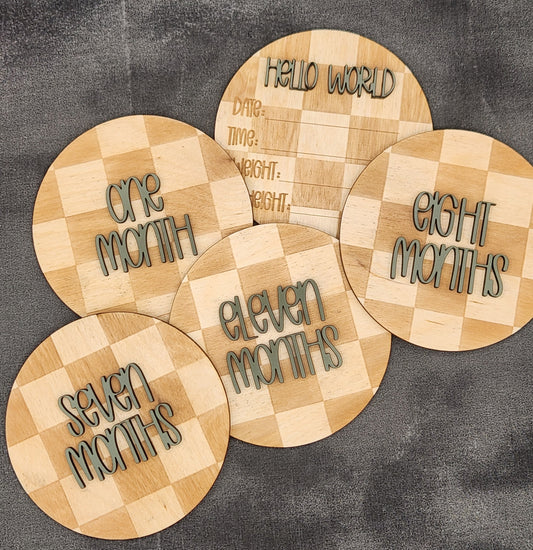 Wooden plaques with milestone text on a gray surface