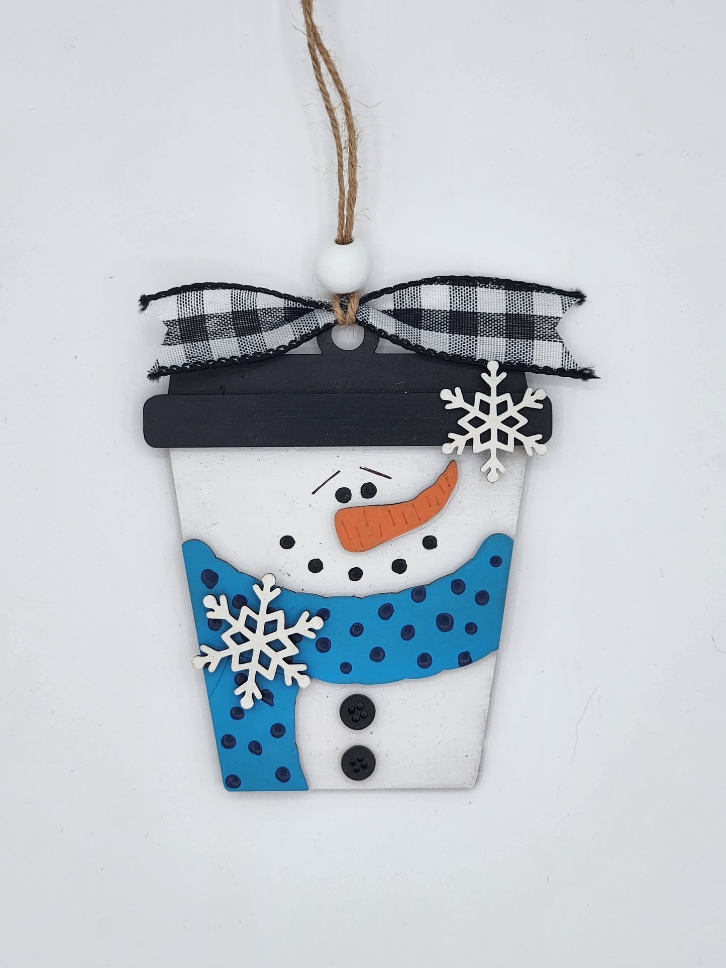 Decorative snowman ornament with blue scarf, black hat, and checkered ribbon on a white background