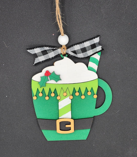 A DIY ornament shaped like a mug with cocoa and painted like an elf outfit.