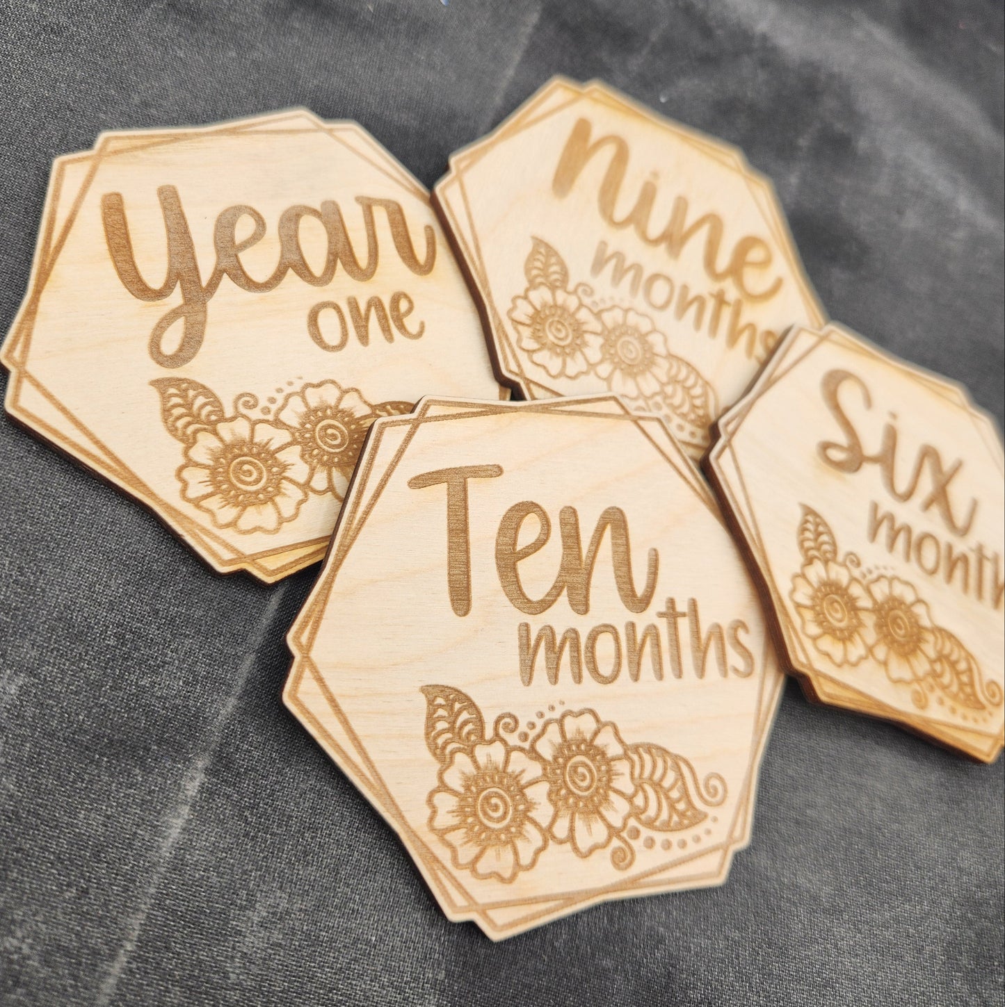 Wooden milestone markers with engraved text on a dark fabric background