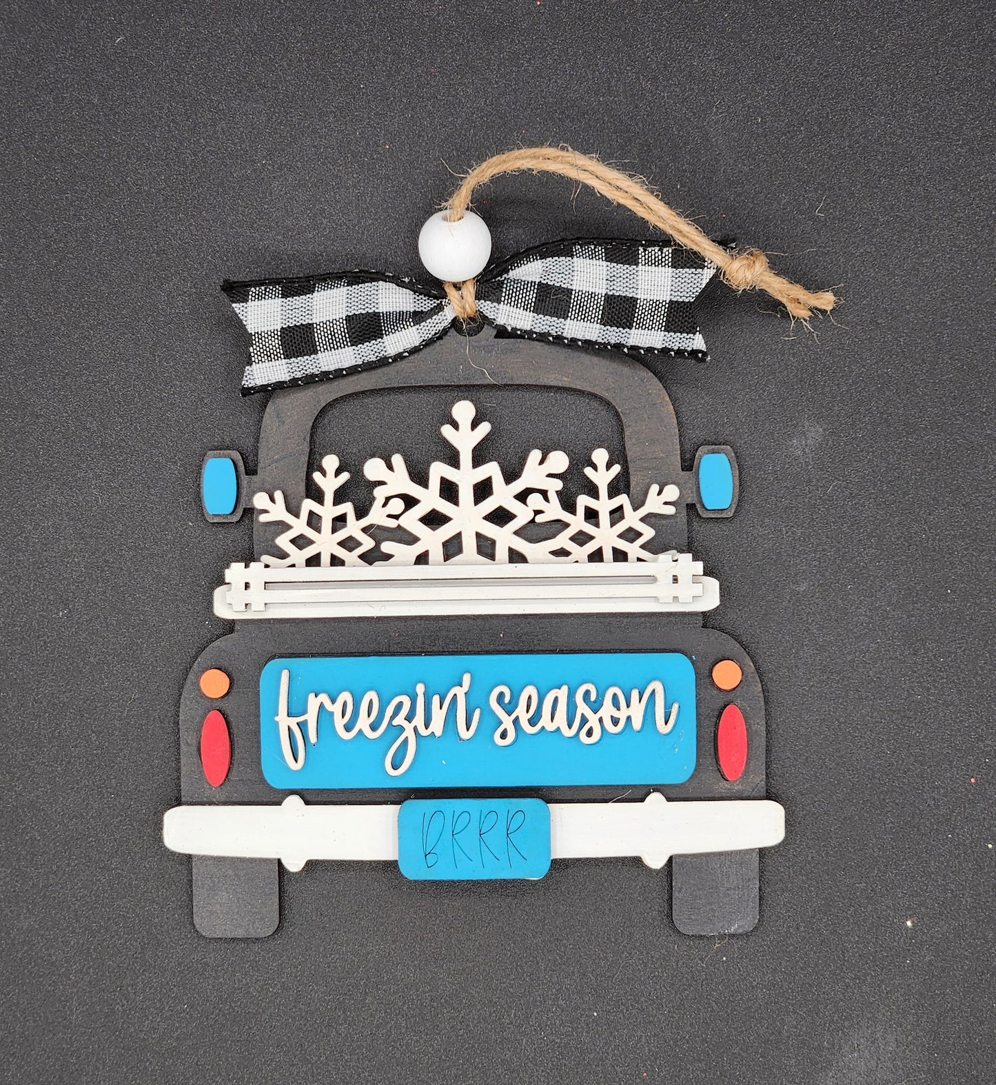 A decorative truck ornament with a 'Freezin' Season' text on the back of a truck.