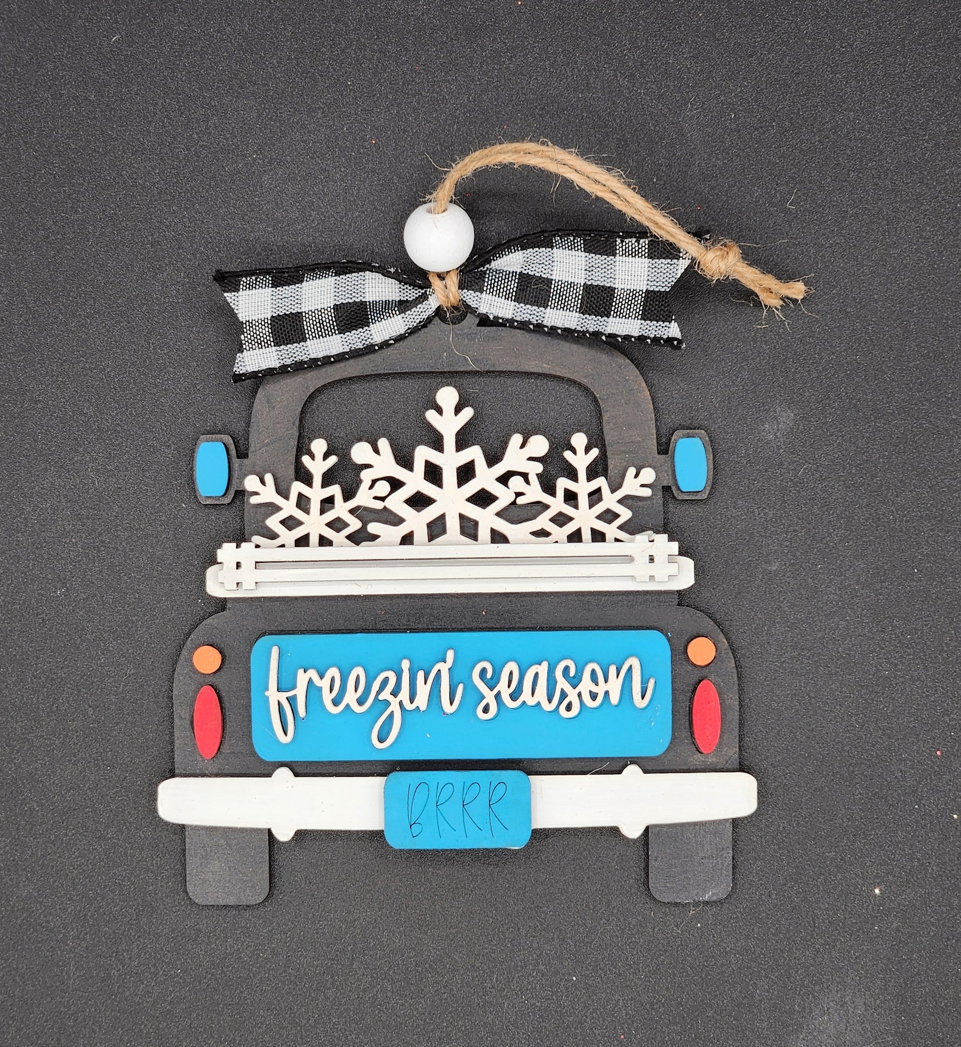 A decorative truck ornament with a 'Freezin' Season' text on the back of a truck.