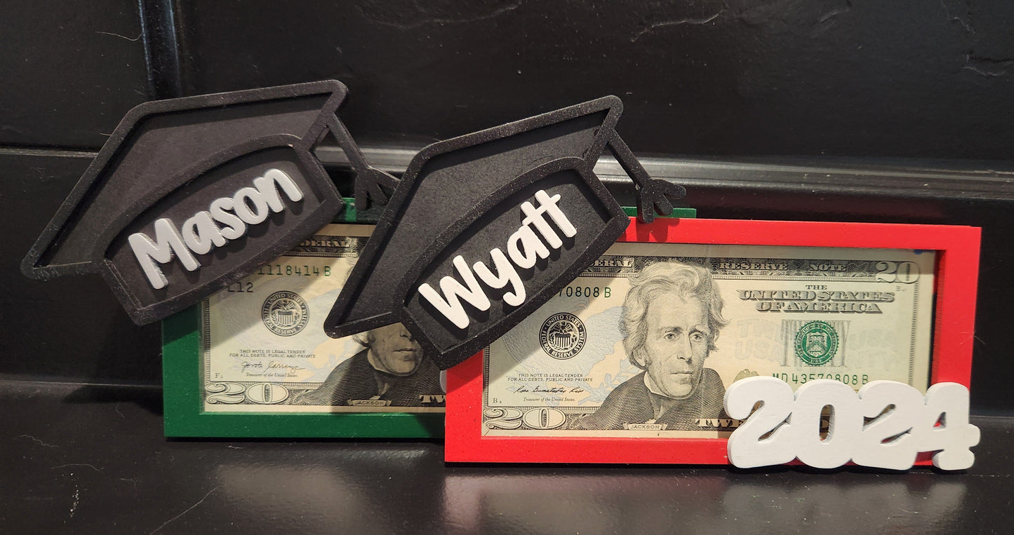A personalized money holder featuring a graduation cap and a year, in colors red, green, and black, with the names 'Mason' and 'Wyatt' on it.