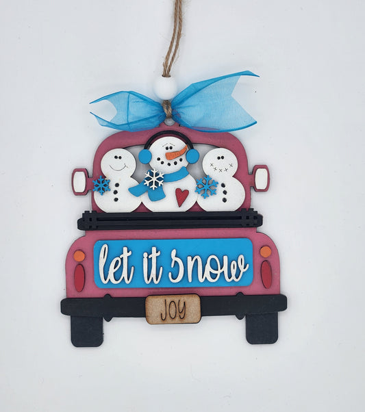 A craft kit to make a decorative truck ornament with 'let it snow' text, featuring snowmen.