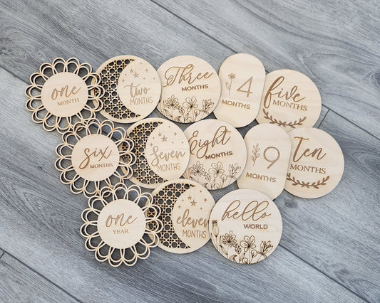A collection of wooden discs with text and numbers on them, laid out on a wooden surface. Each disc has a different number ranging from 1 to 11 months.