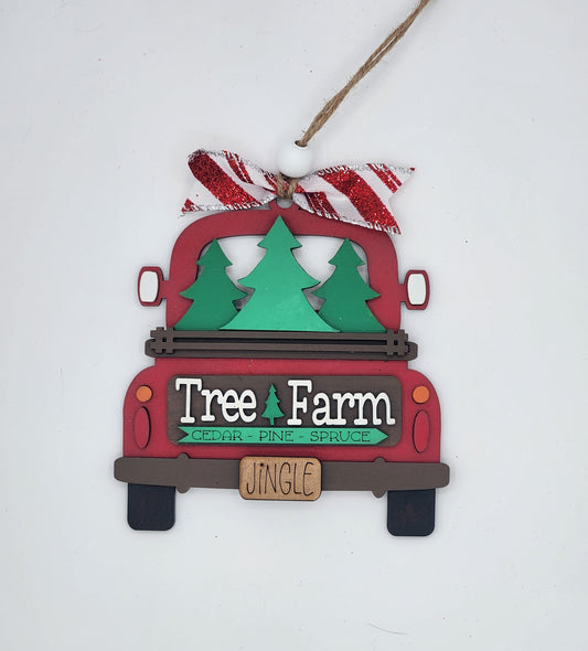 A craft kit to make a decorative truck ornament with a 'Tree Farm' and 'JINGLE' sign, featuring red and green colors and a Christmas tree in the bed of the truck.